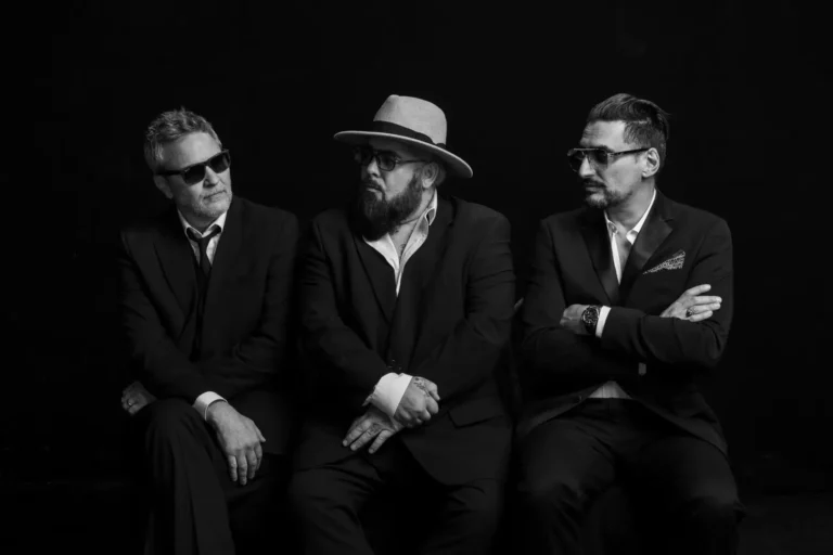 Fun Lovin' Criminals posing for a photo wearing suits.