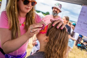 A woman applying face paint to a gatherer.